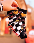 Person holding a checkered sock with a blurred amusement park background
