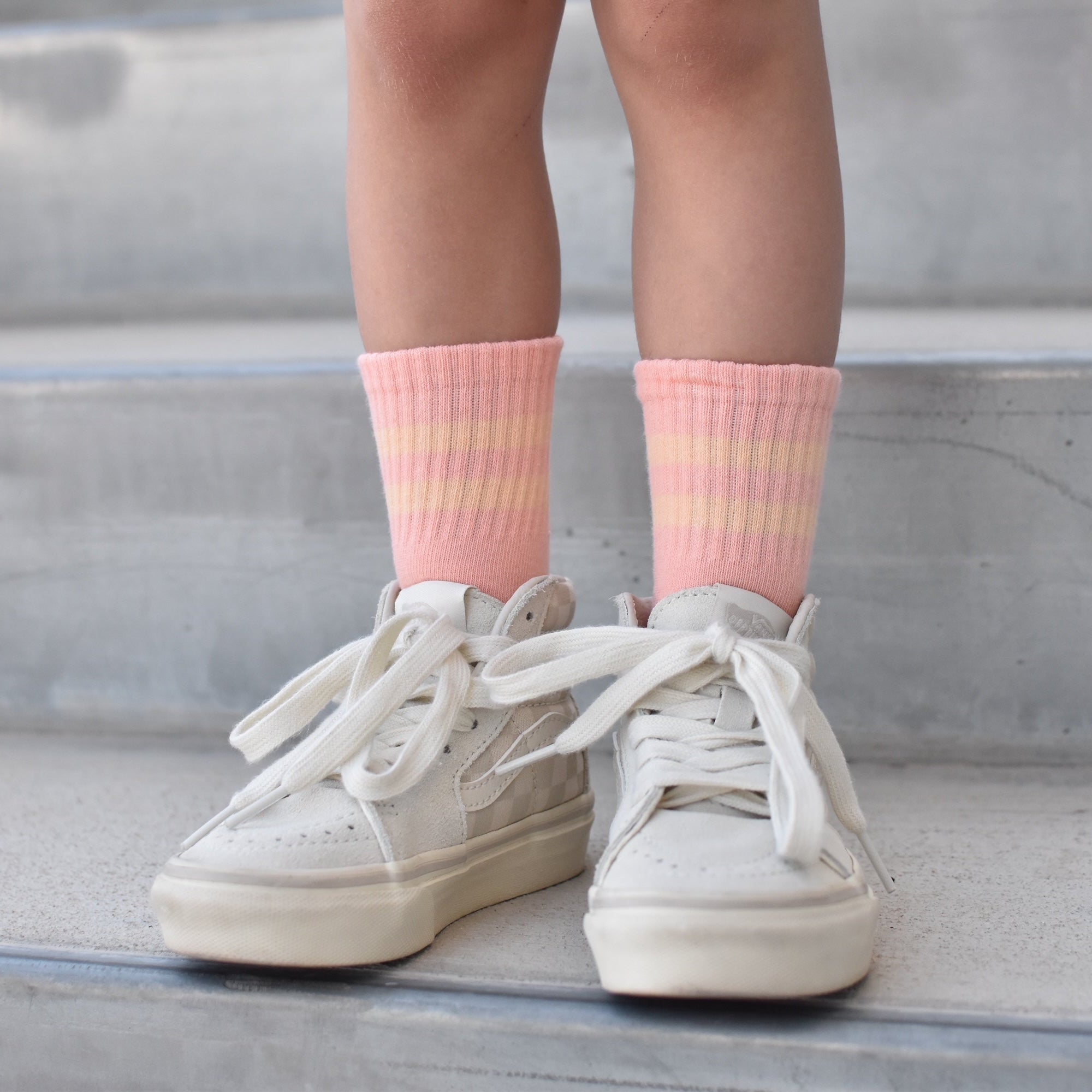 White sneakers and pink socks on a concrete surface
