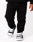 toddler wearing black sponge fleece jogger sweatpants walking forward neutral studio background
