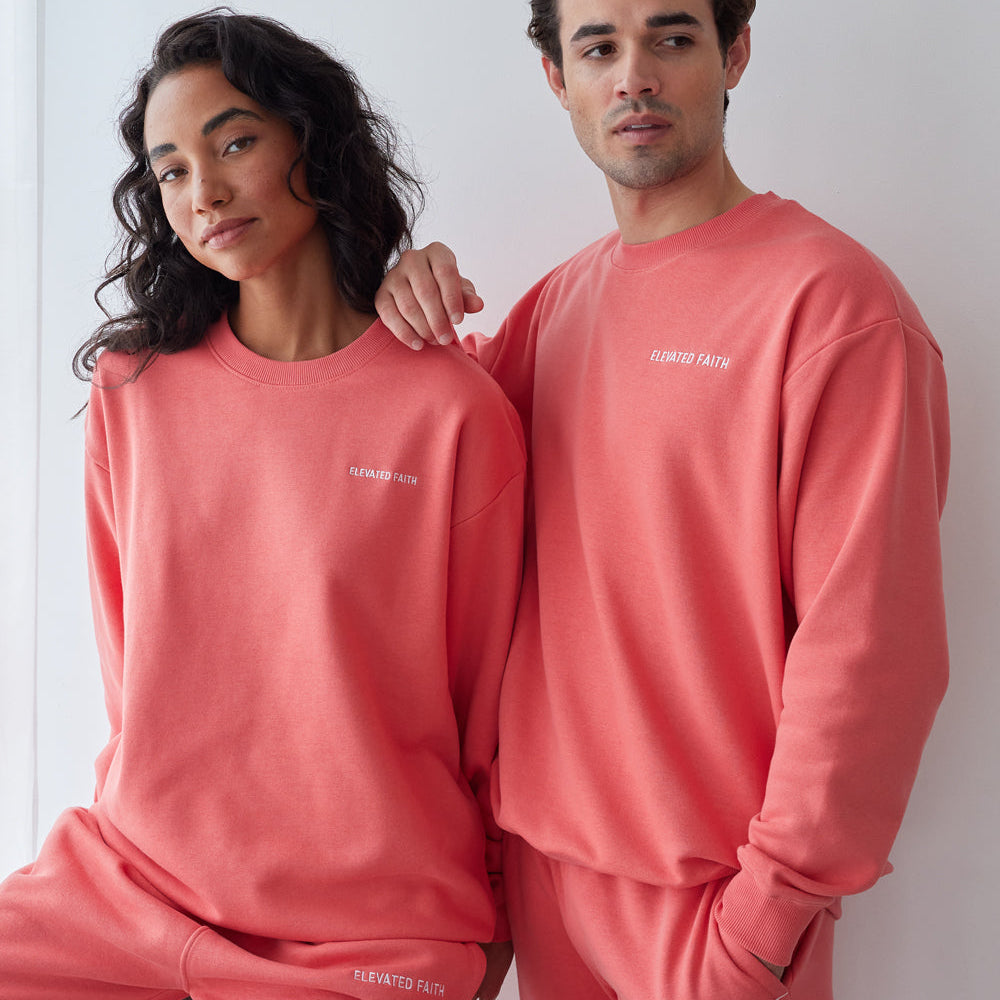 Two people wearing matching pink sweatshirts and pants with a brand logo.
