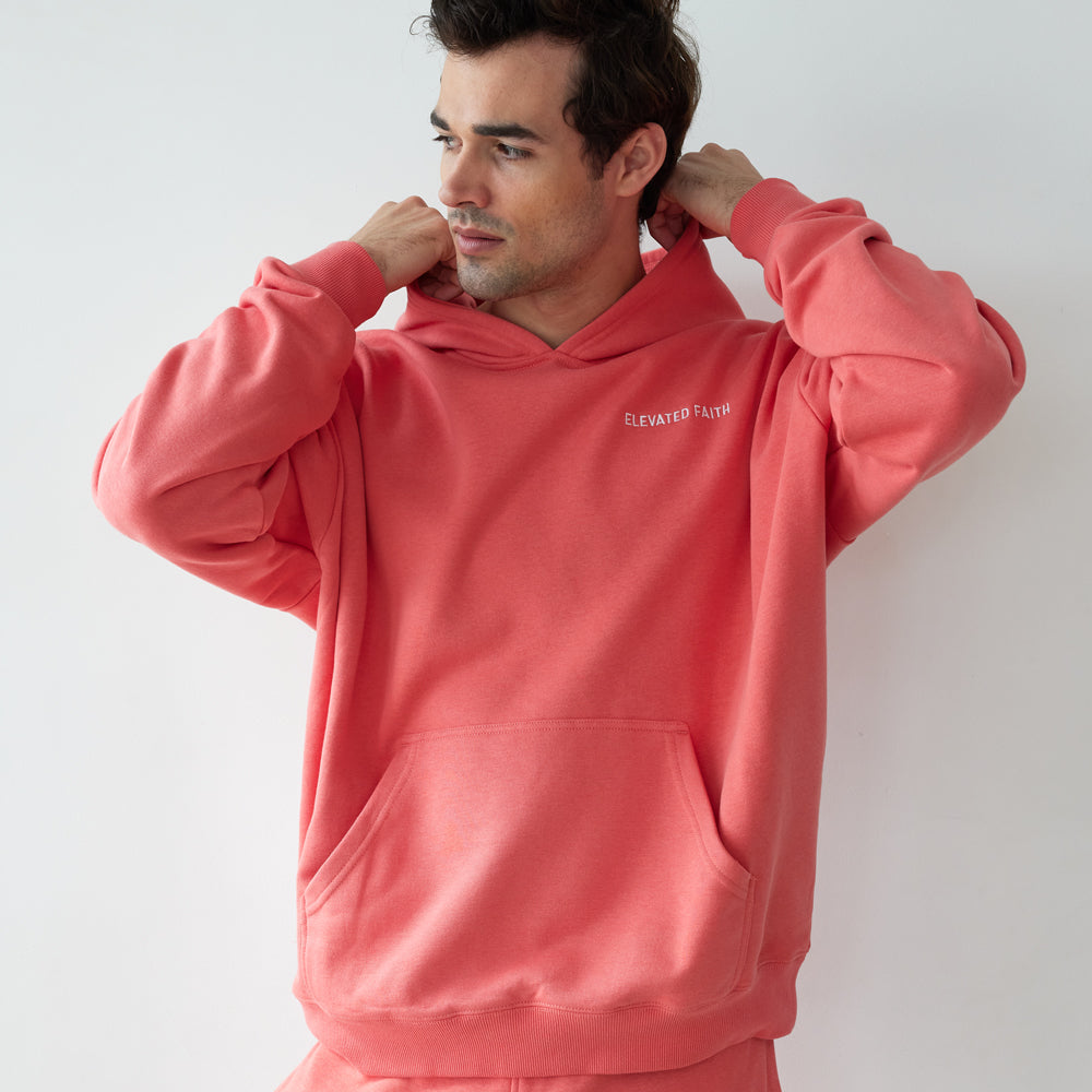 Man wearing a pink hoodie and pants with a brand logo on a white background