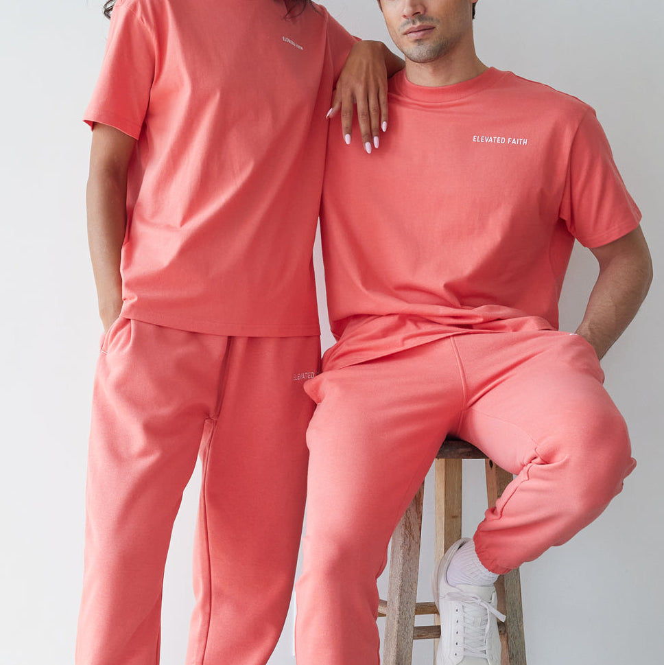 Two people wearing matching pink outfits against a plain background