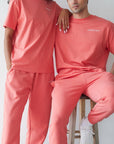Two people wearing matching pink outfits against a plain background