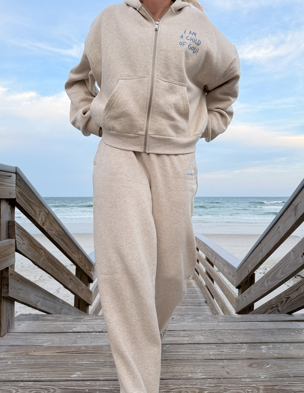 Heather Eggshell Basics sweatpants styled with a coordinating zip hoodie on a beach boardwalk.