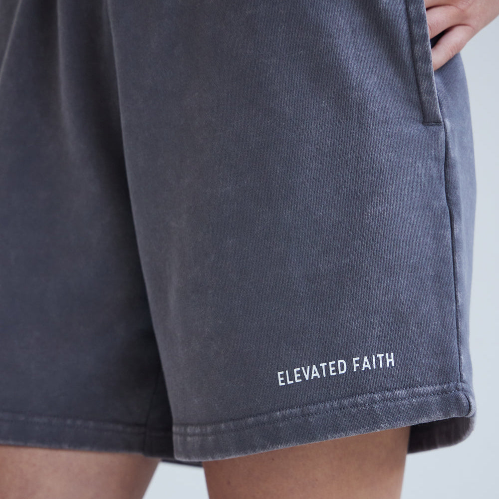 Navy shorts with 'Elevated Faith' branding on a light gray background
