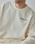 Man wearing a cream-colored sweatshirt with 'Elevated Faith' text on a plain background