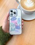 Hand holding an iPhone in the pastel Be Joyful phone case beside a cup of coffee