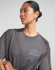 Close-up of blue Believe in Miracles lettering on the front of a Lamp Black heavyweight tee