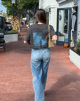 Model walking outdoors in the Believe in Miracles tee and jeans with the blue back graphic visible