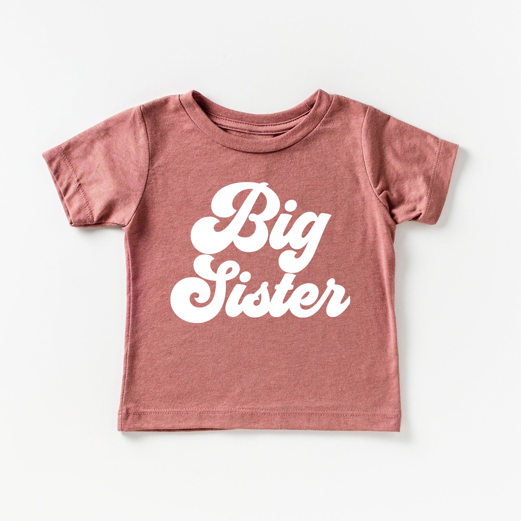 Pink t-shirt with 'Big Sister' text on a white background
