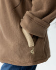 Close-up of the Chestnut fleece pullover showing a cream pocket zipper and embroidered logo.
