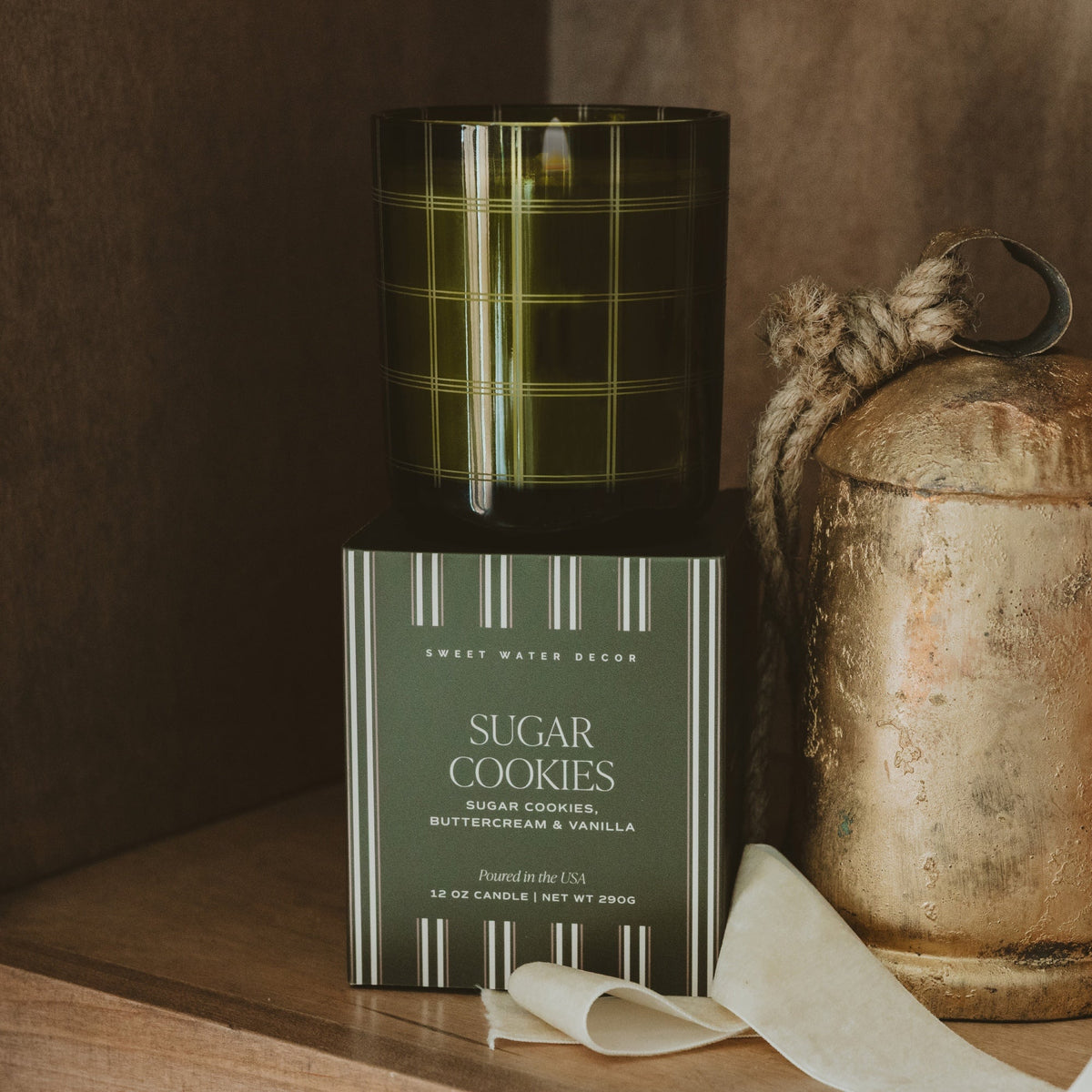 Sugar Cookies soy candle in an olive glass jar displayed above its coordinating green gift box.