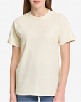 Young woman wearing an ivory Comfort Colors Heavyweight T-Shirt, styled casually with a relaxed unisex fit — ideal for custom printing and everyday comfort by Lumiere Vive.