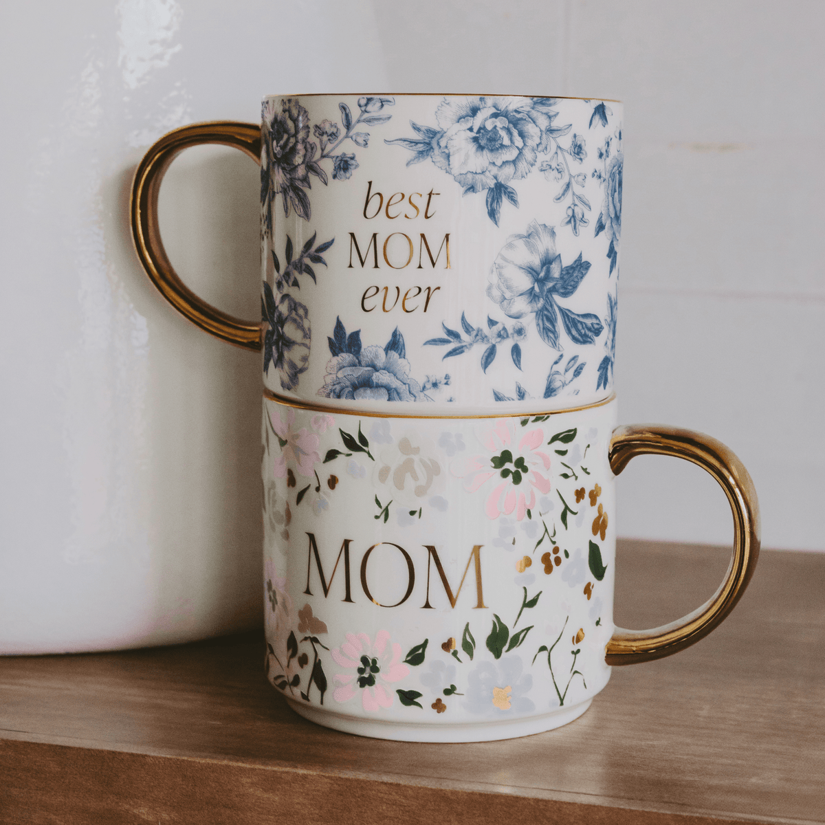 Blue floral Best Mom Ever mug stacked above a coordinating floral Mom mug