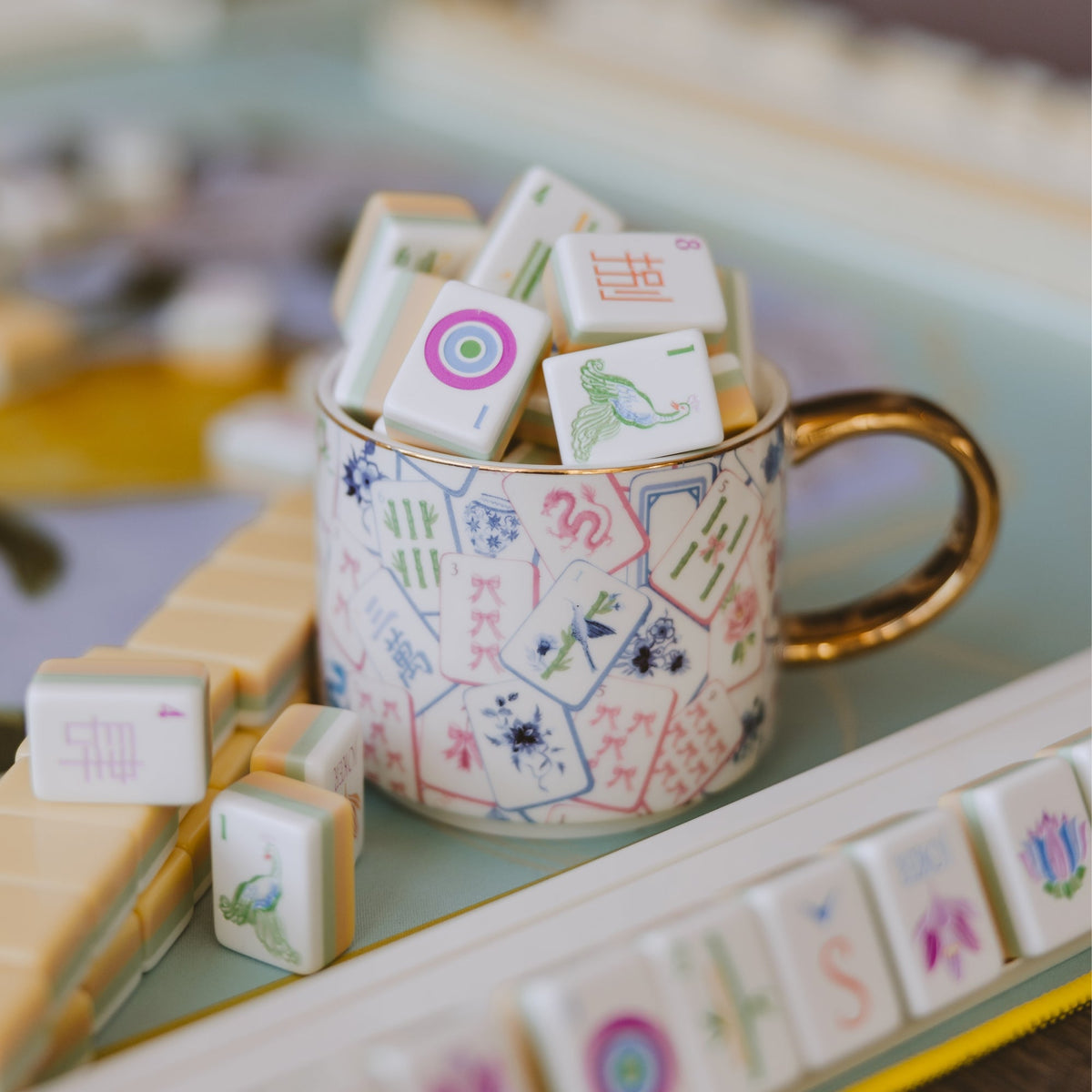 Mahjong gold handle mug filled with game tiles beside a mahjong tile rack