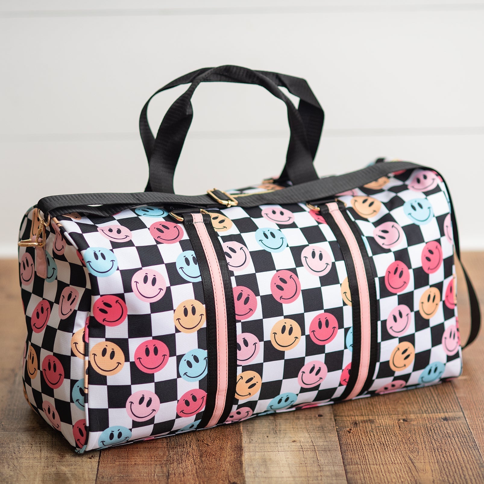 Duffel bag with smiley face pattern on a wooden floor