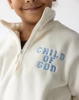Close-up of blue Child of God chest embroidery and the partial-zip collar on cream fleece
