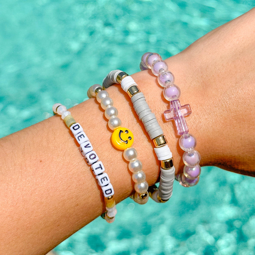 Wrist with multiple bracelets against a pool background