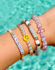 Wrist with multiple bracelets against a pool background