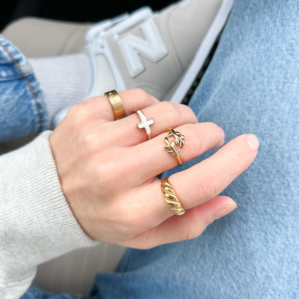 Hand wearing multiple gold rings with a blurred background