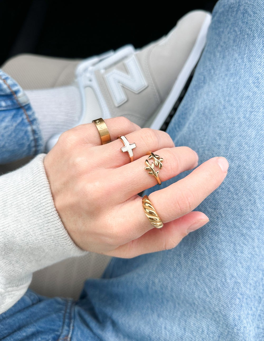 Hand wearing multiple gold rings with a blurred background