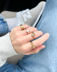 Hand wearing multiple gold rings with a blurred background