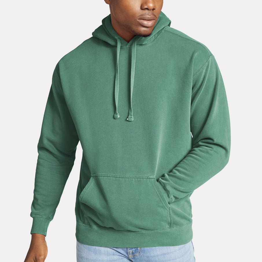 Male model wearing a seafoam green Comfort Colors garment-dyed hoodie, featuring a relaxed fit and front pocket — ideal for custom printing by Lumiere Vive.