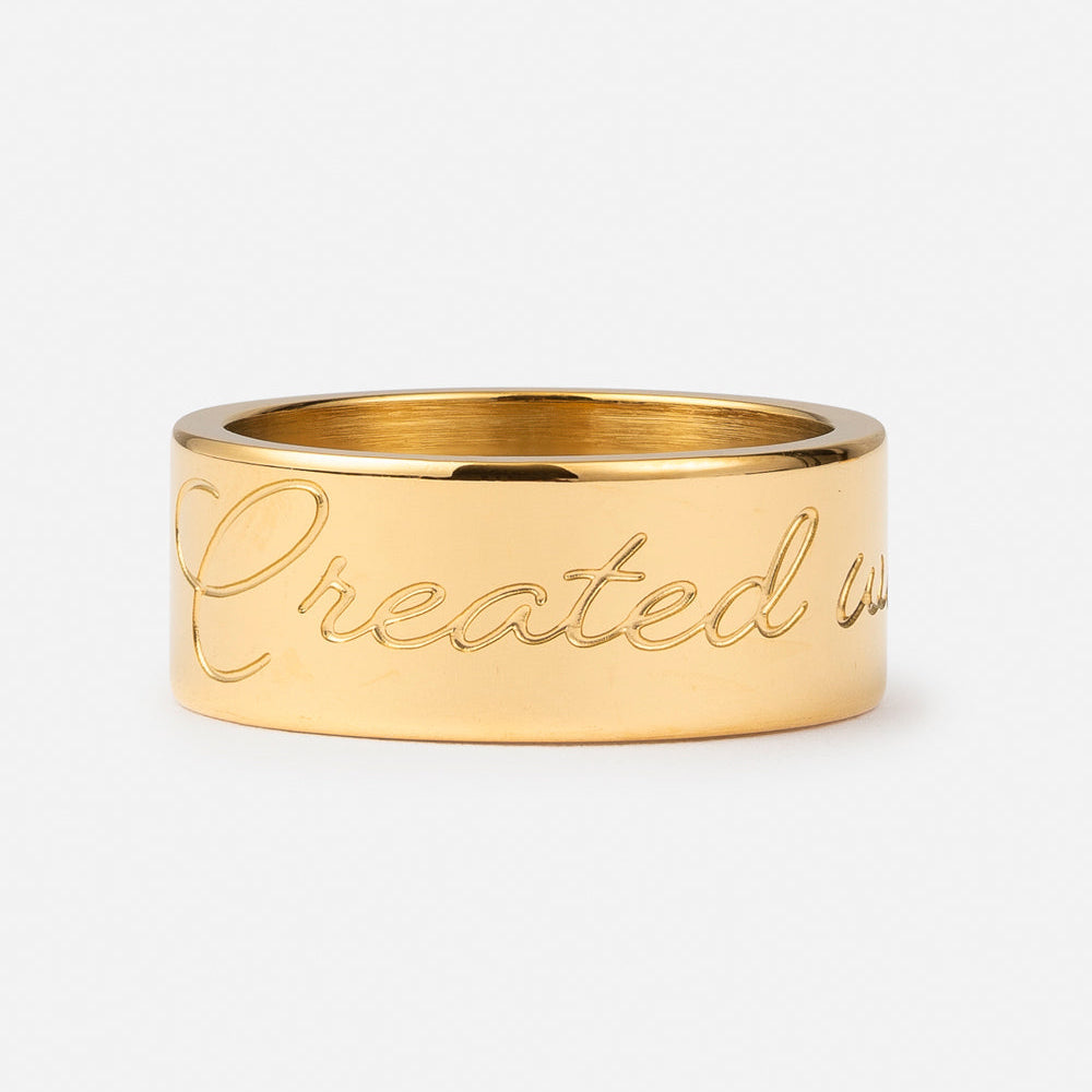 Gold ring with 'Created with' engraving on a white background