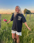 Model holding flowers while wearing the black floral graphic tee with a white skirt.