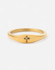 Gold-tone ring with a smooth tapered band and small cross featuring a clear gemstone accent on a white background
