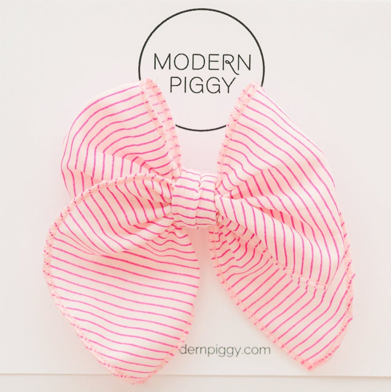 Pink striped hair bow with 'Modern Piggy' branding on a white background