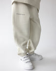 Close side view of Deeply Loved lettering on Moonstone kids sweatpants worn with white sneakers