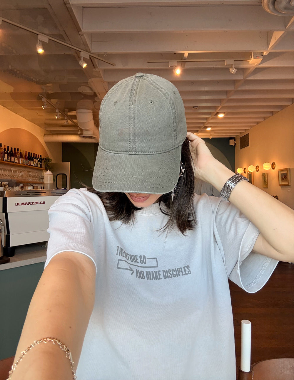 Model wearing the Chateau Grey Disciples Heavyweight Tee with a small front chest design and a cap