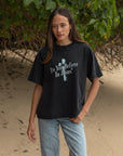 Woman wearing the black Do You Believe in Jesus tee with light blue jeans outdoors.