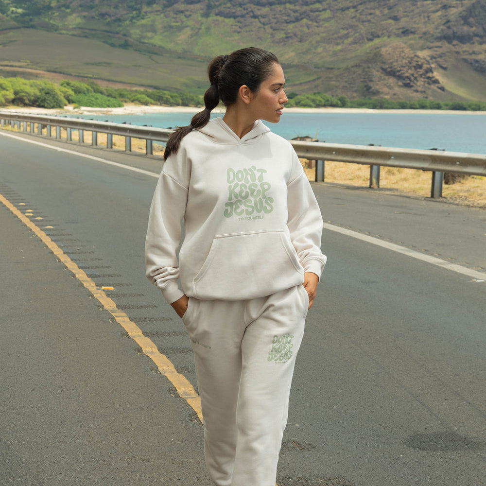 Person wearing a white hoodie and pants with text on a road with a scenic background