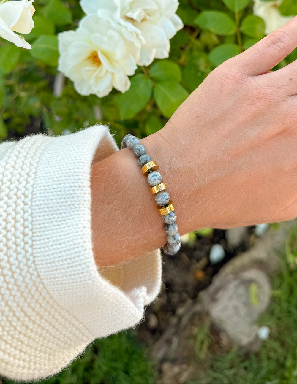 Faith Hope Love beaded bracelet worn on a wrist beside white flowers