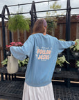 Back view of the Bluebell Follow Jesus sweatshirt worn outside a flower shop