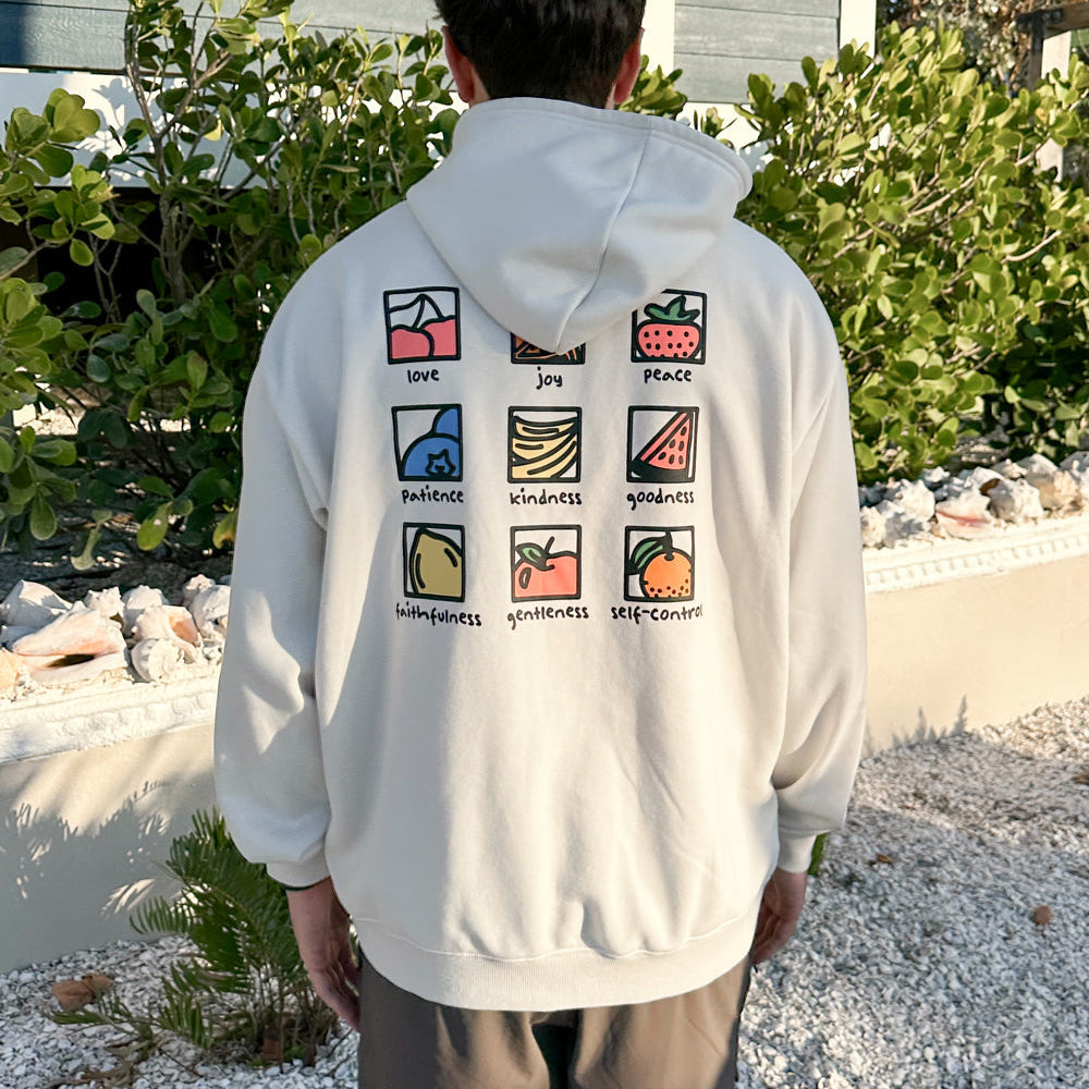 Person wearing a white hoodie with colorful symbols and text on the back, standing outdoors.