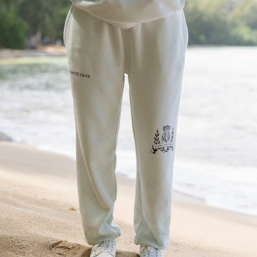 Person wearing a light-colored tracksuit with logos on the beach