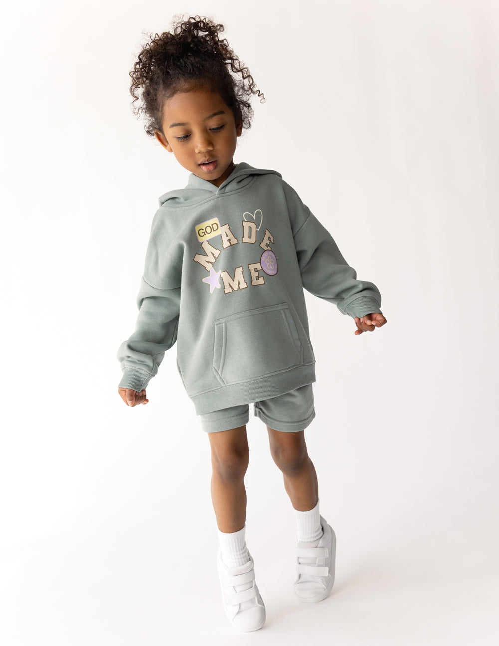 Child wearing the Millstone Grey God Made Me Kids Hoodie with coordinating shorts and white sneakers