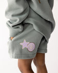 Close-up of Millstone Grey God Made Me kids shorts with pastel star and flower graphics