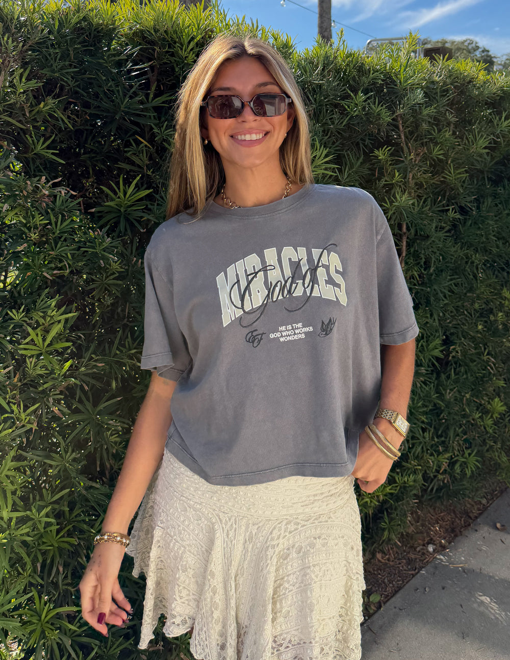 Model wearing God of Miracles cropped tee with a cream skirt