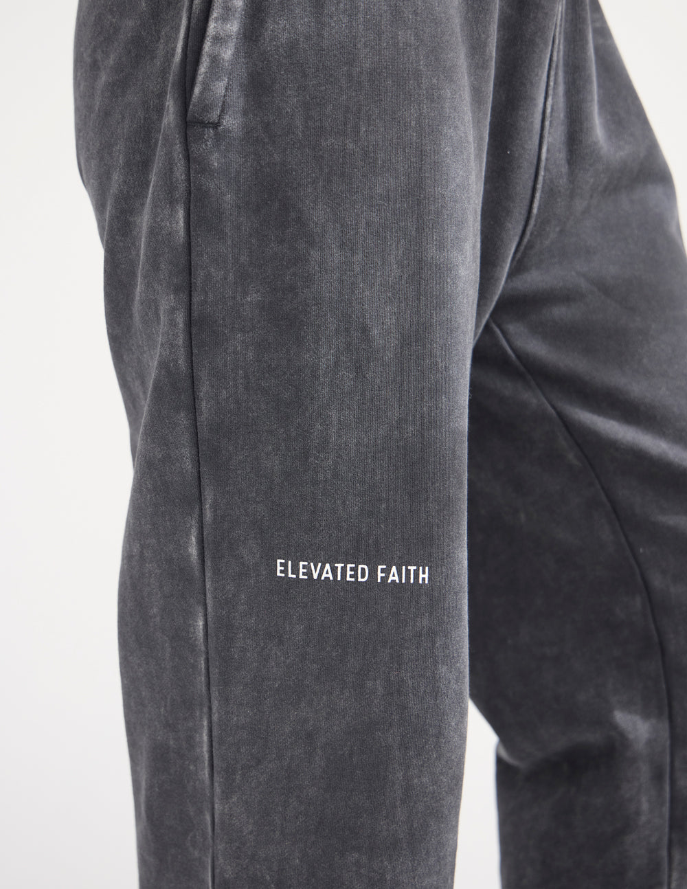 Close-up of Elevated Faith lettering embroidered on the black sweatpants.
