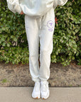 Front view of God’s Plan Racing Icicle Sweatpants with purple graphics, styled with white sneakers
