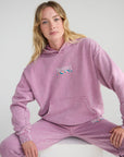 Woman seated in the Bordeaux God’s Promises Hoodie, showing the front graphic and relaxed fit.