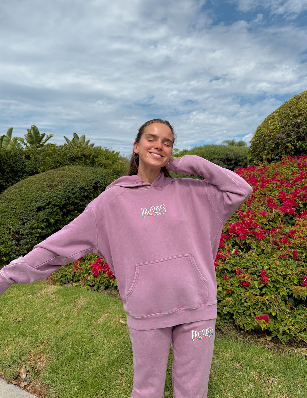 Woman wearing the God’s Promises Hoodie and coordinating pants with her arms extended outdoors.