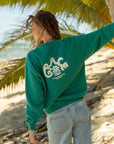 Back of the Grace Greenlake crewneck sweatshirt with cream lettering and a floral accent at the beach