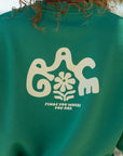 Close-up of cream Grace lettering and the floral accent on the back of a green crewneck sweatshirt