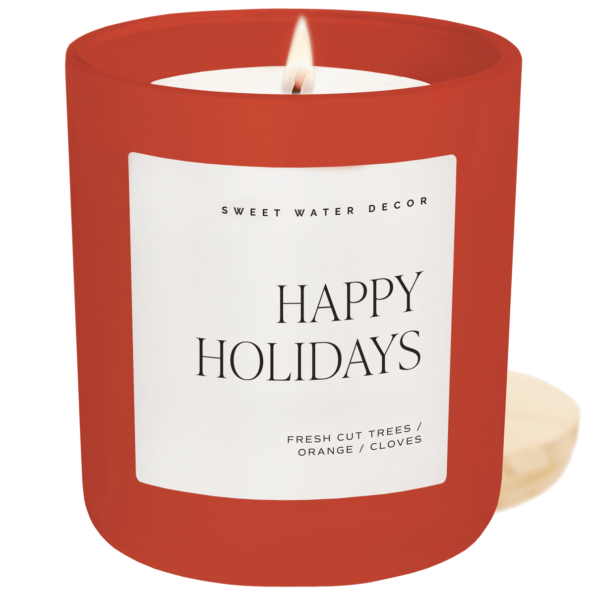 Happy Holidays soy candle in a red matte jar with a white label and wood lid beside it