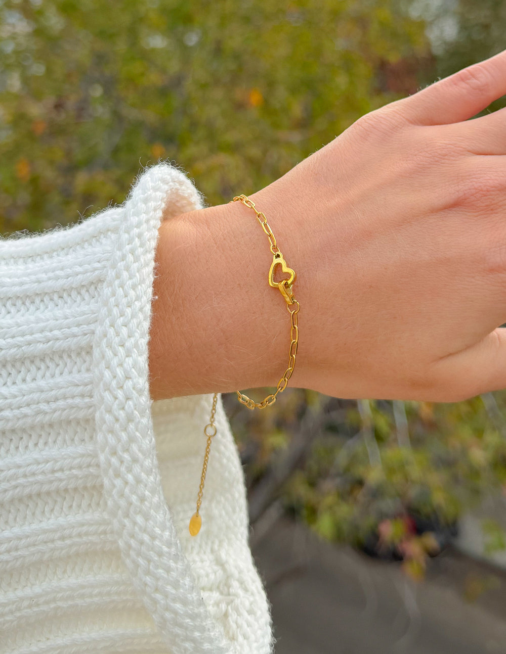 Heart Paperclip Chain Bracelet worn on a wrist with a light-colored knit sweater outdoors